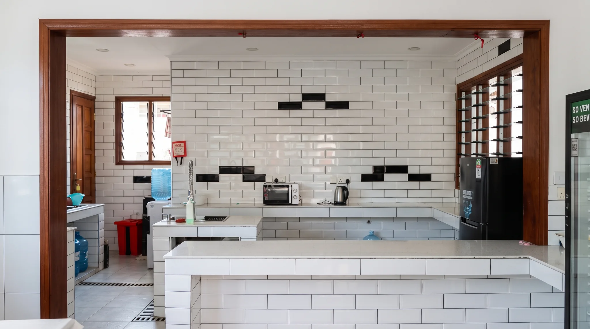 Communal kitchen food preparation counter with stainless steel sink, dishware and cooking utensils