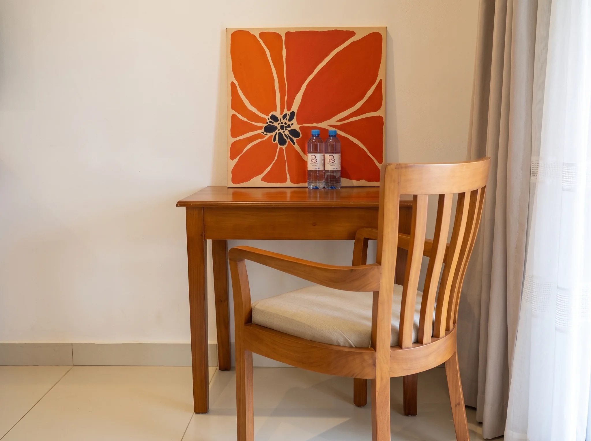 Deluxe Studio Room wooden study desk and comfortable work chair with complimentary bottled water at Diani Darling Cottages
