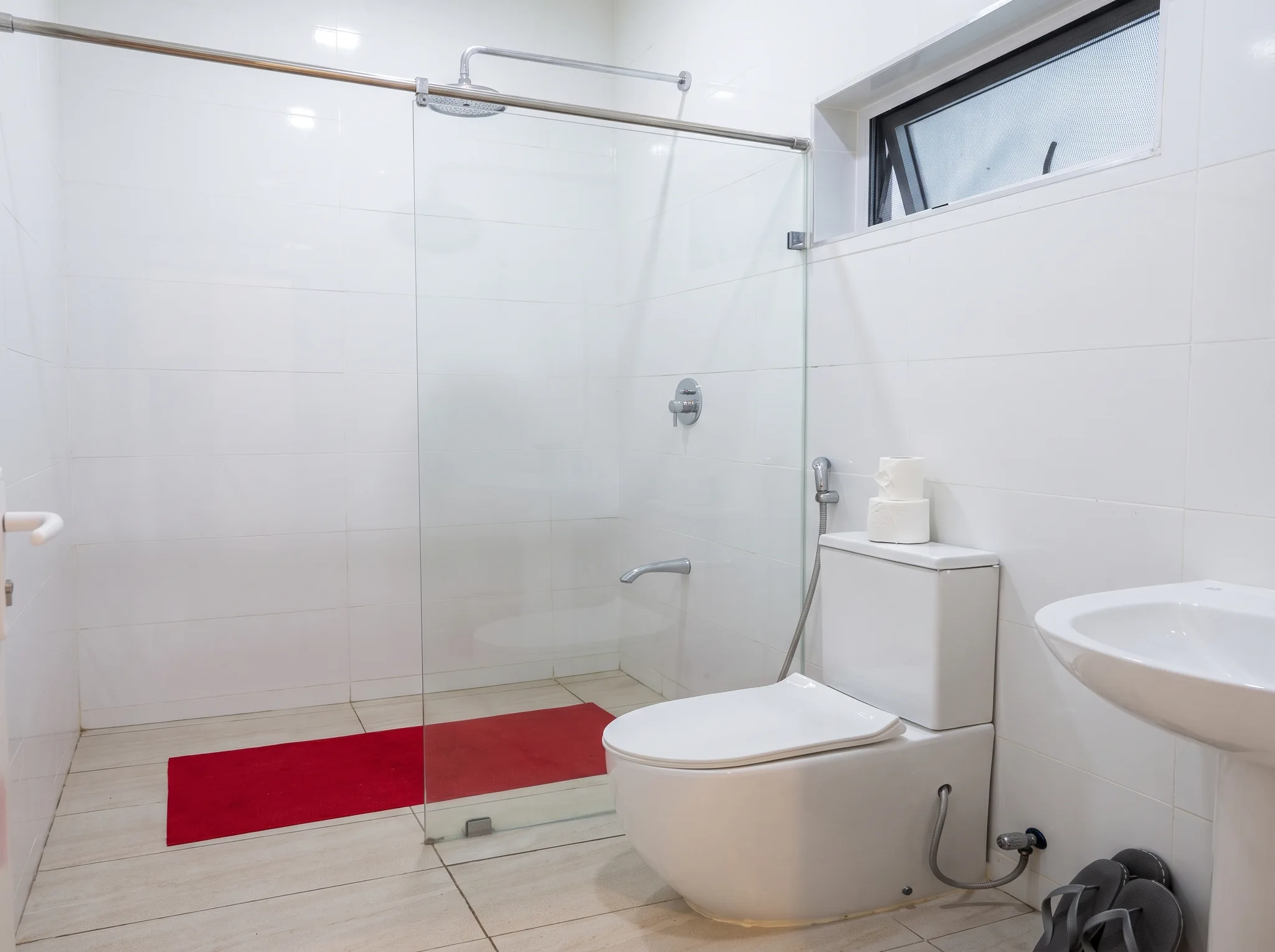 Modern en-suite bathroom with glass walk-in rainfall shower, bidet sprayer and ceramic fixtures at Diani Darling