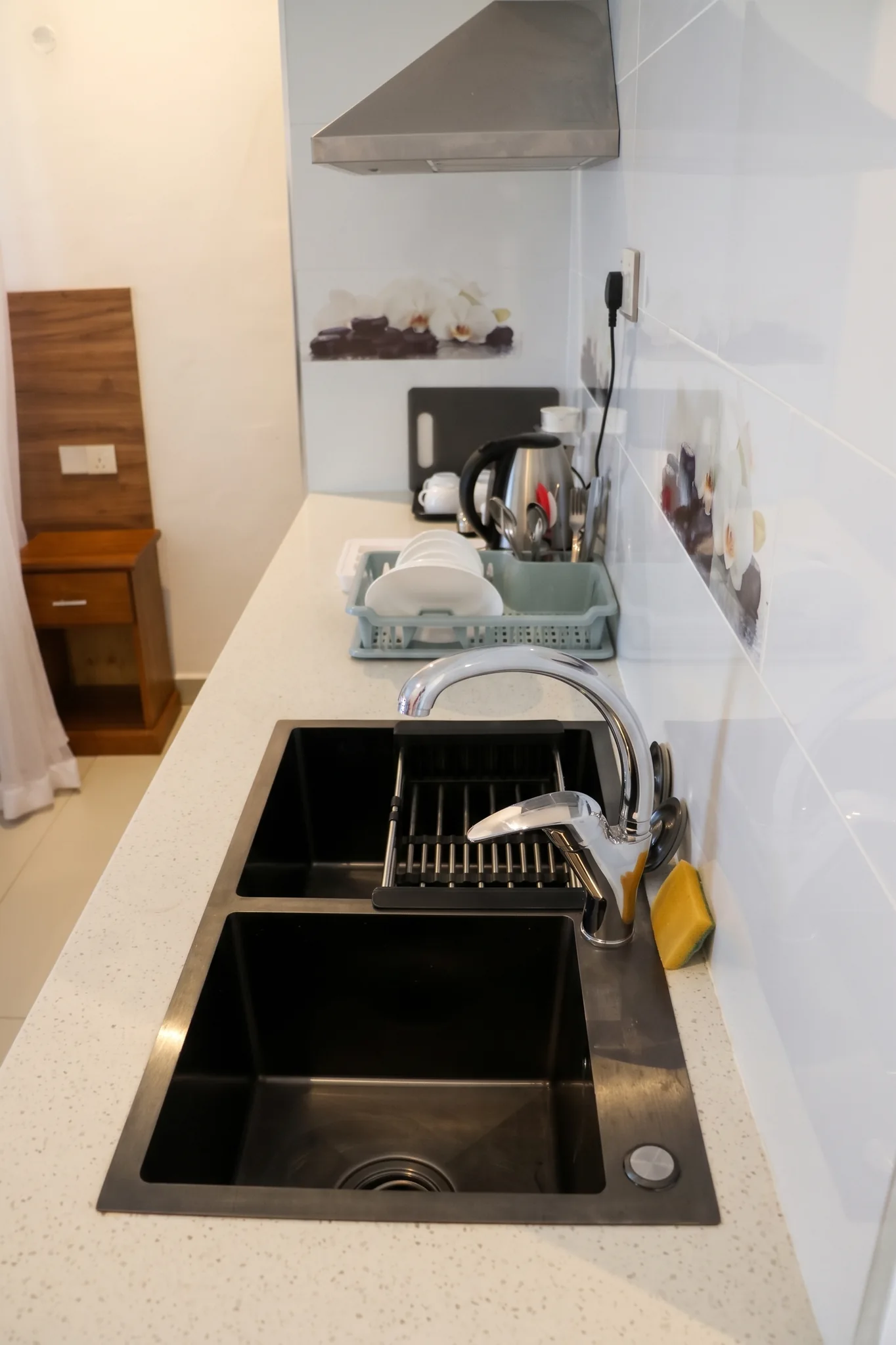Detailed view of the modern studio kitchenette featuring black granite composite sink, gooseneck faucet and electric kettle