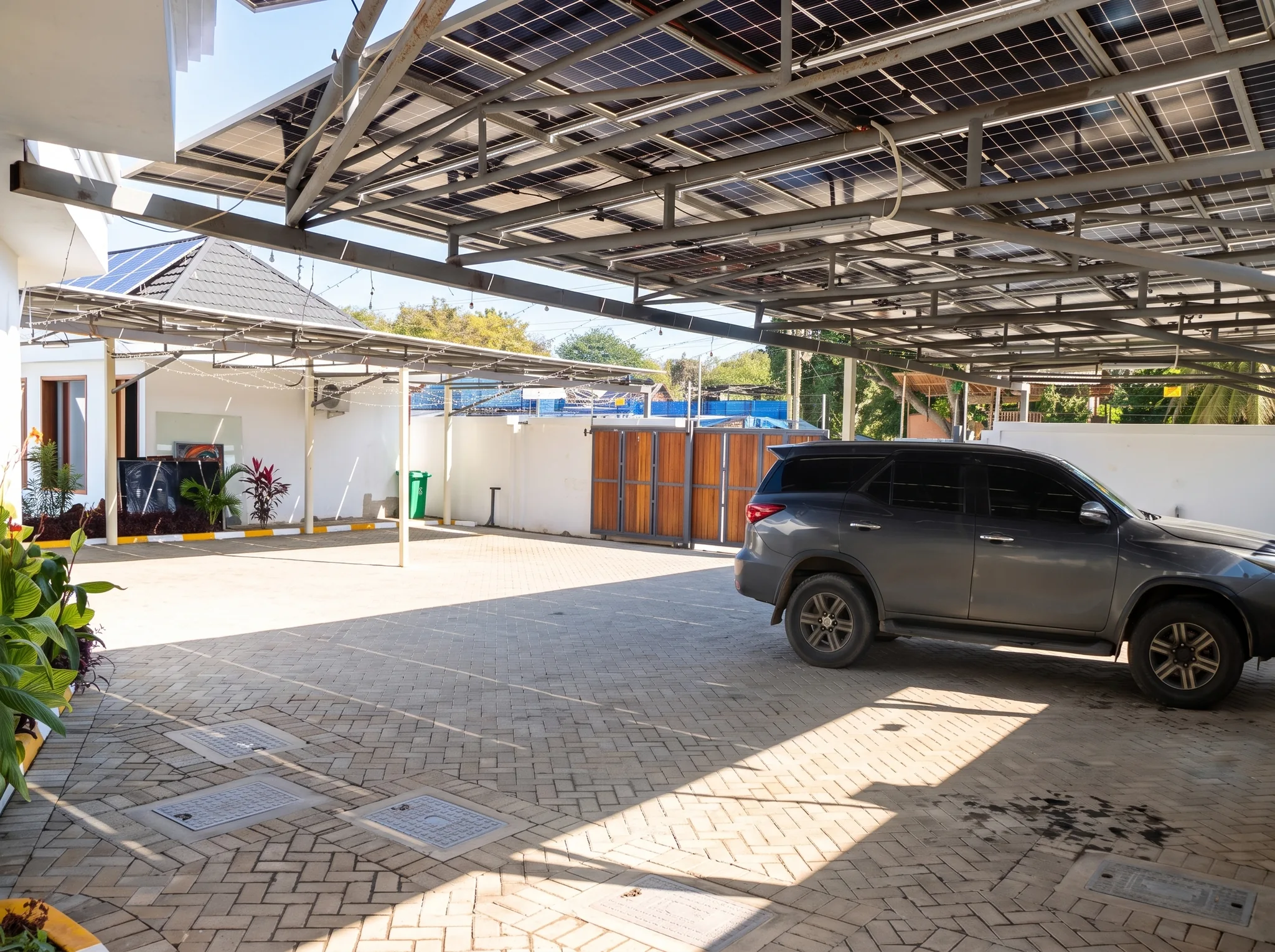 Secure covered vehicle parking bay with solar panel canopy and cabro paving at Diani Darling Cottages