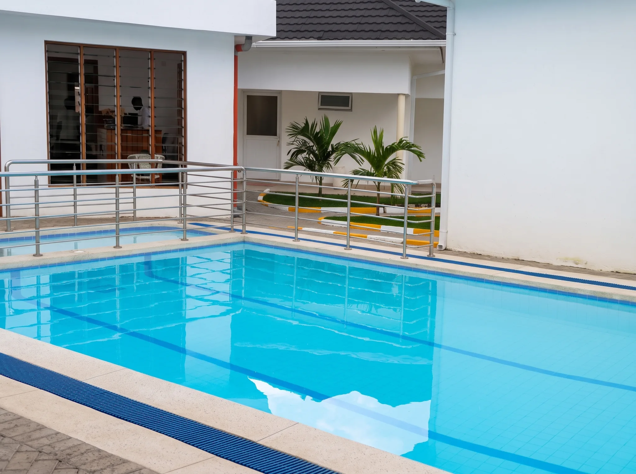 Crystal clear swimming pool with lap lines and stainless steel ladder under coastal Kenyan sun at Diani Darling