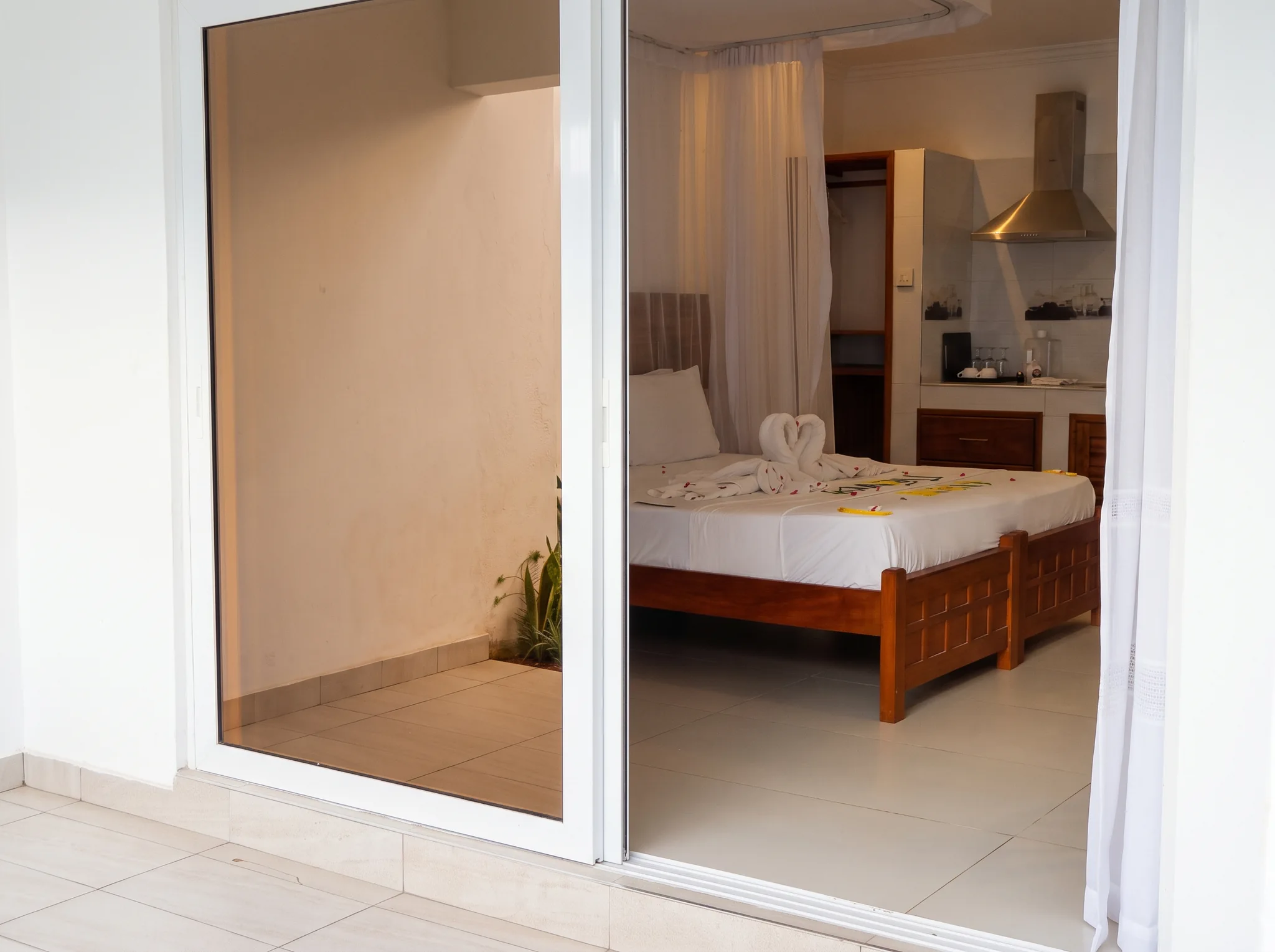 Scenic view from private veranda into luxury studio cottage showing king bed with swan towel art and kitchenette