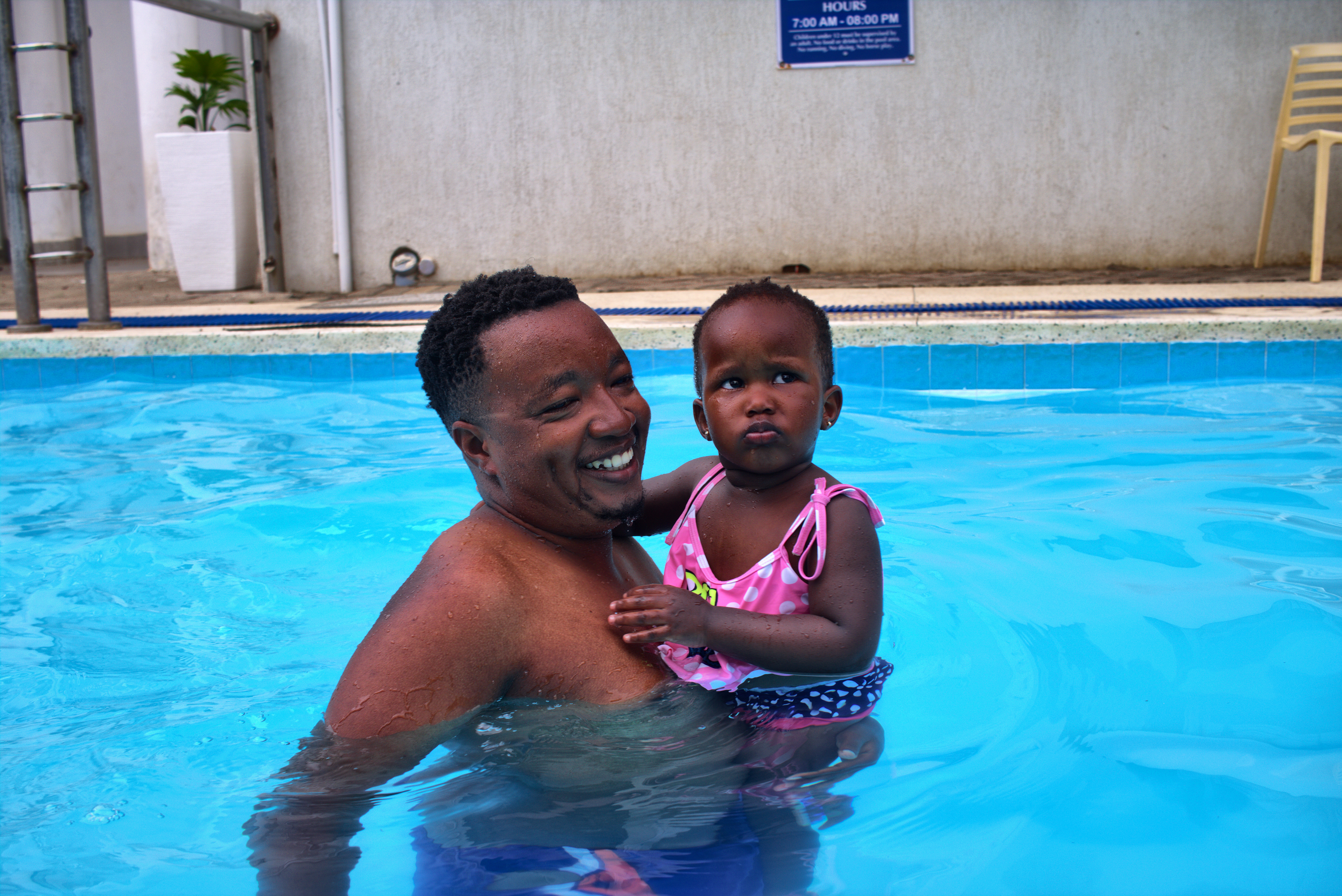 Father Holding Baby Daughter in Resort Pool